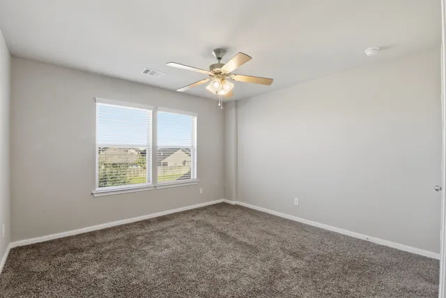 an empty room with windows and fan