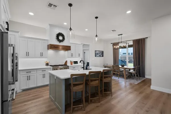 a kitchen with stainless steel appliances granite countertop a stove a sink a oven a dining table and chairs with wooden floor