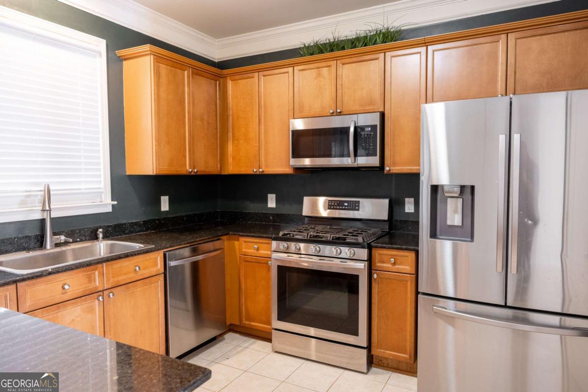 1232 Harris Commons Place, Unit 1232 Roswell, GA 30076 - Photo 9 of 21 a kitchen with stainless steel appliances granite countertop a refrigerator sink stove microwave and cabinets