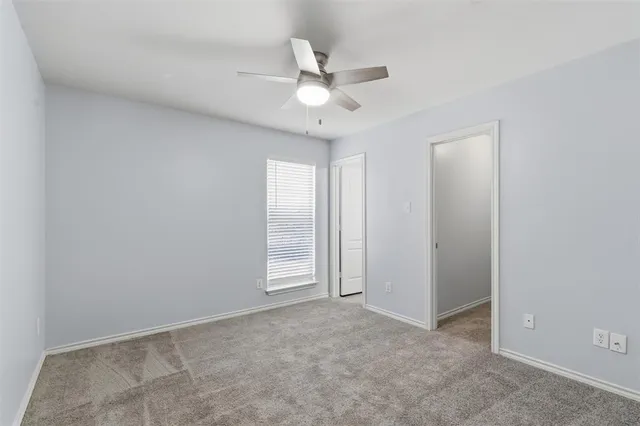 an empty room with closet and a ceiling fan
