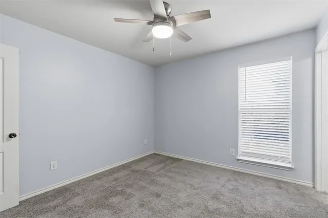 an empty room with a window and a fan