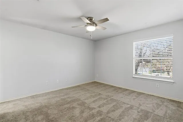 an empty room with a window and a ceiling fan