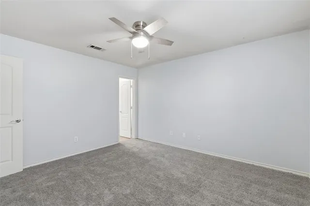 an empty room with a fan & a window