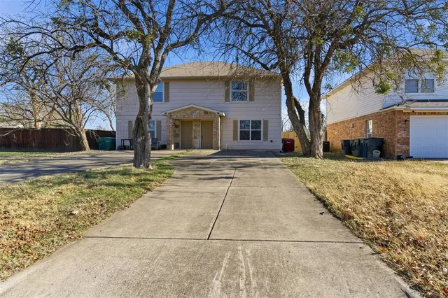 a front view of a house with large trees