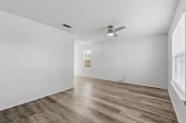 an empty room with wooden floor and ceiling fan