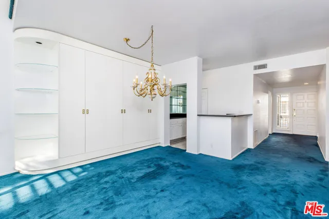 a view of a kitchen with an empty room and wooden floor