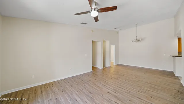 an empty room with wooden floor ceiling fan and window
