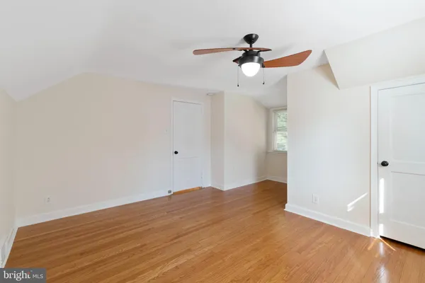 a view of empty room with wooden floor and ceiling fan
