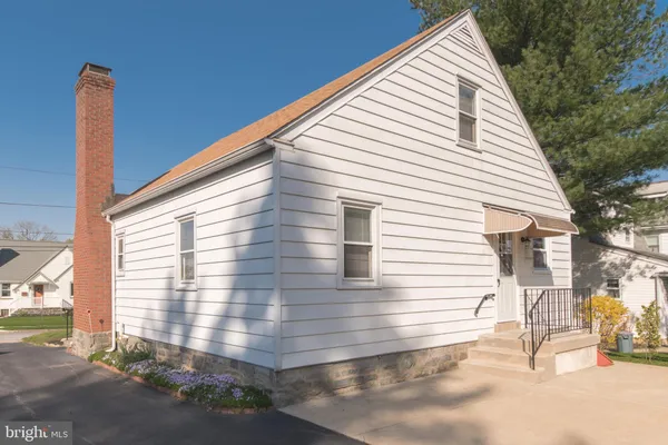 a view of a white house with a big yard and large tree