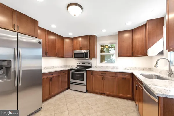 a kitchen with stainless steel appliances granite countertop a sink stove refrigerator and cabinets