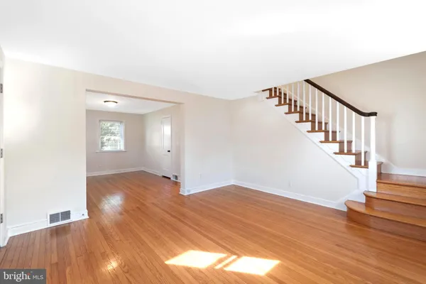 a view of an empty room with wooden floor and stairs