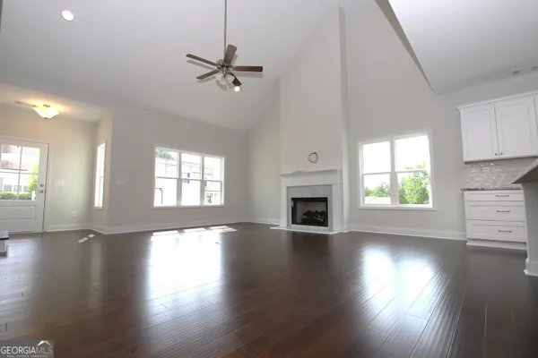 a view of empty room with wooden floor and fan