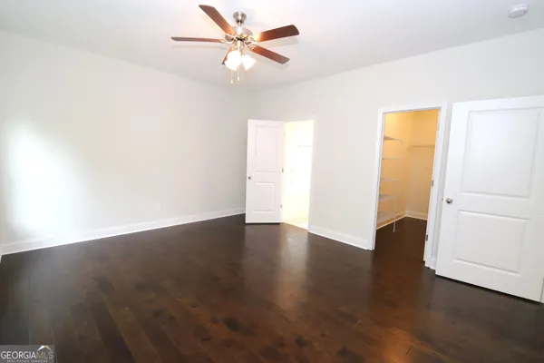 an empty room with wooden floor fan and windows