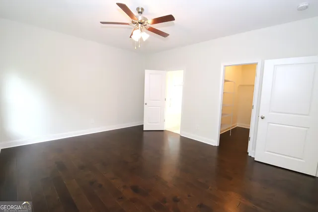 an empty room with wooden floor fan and windows