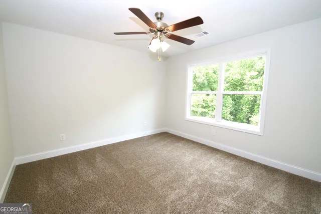 an empty room with a window and a ceiling fan