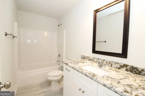 a bathroom with a granite countertop sink toilet a shower and a bathtub