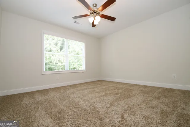 an empty room with a window and a fan