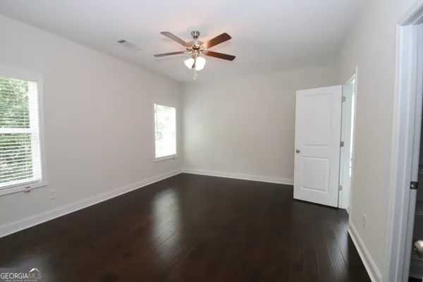 an empty room with wooden floor fan and windows