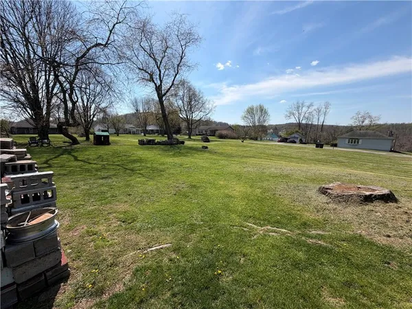 a view of backyard with wooden fence and large trees