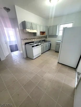a kitchen with granite countertop a stove a sink and a refrigerator
