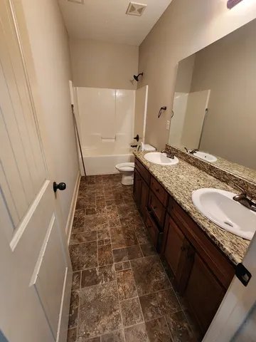 a bathroom with a granite countertop sink a toilet a mirror and vanity