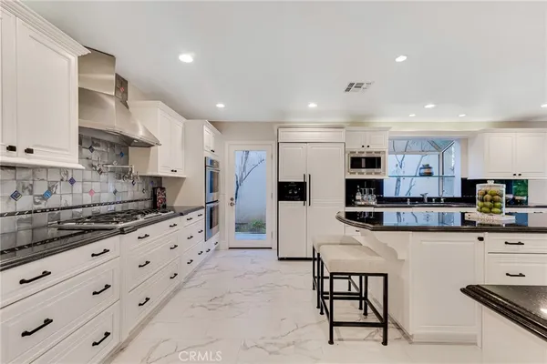 a kitchen with stainless steel appliances kitchen island granite countertop a refrigerator and cabinets