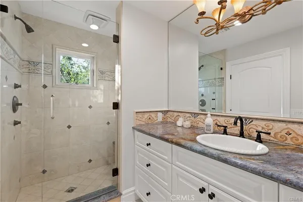 a bathroom with a granite countertop sink a mirror a shower and a bathtub