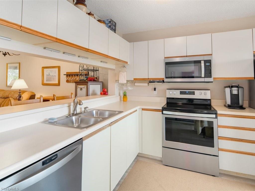 3012 Sandpiper Bay Circle, Unit D301 Naples, FL 34112 - Photo 8 of 23 a kitchen with granite countertop a sink and stainless steel appliances