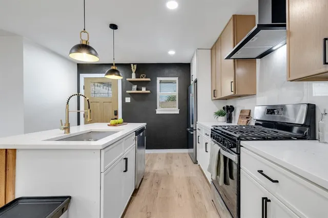 a kitchen with stainless steel appliances granite countertop a sink a stove and a refrigerator