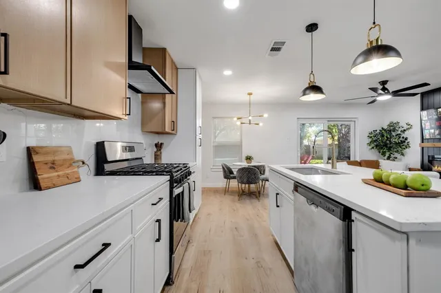 a kitchen with stainless steel appliances granite countertop a sink a stove and a wooden floors