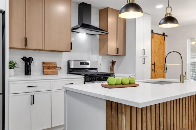 a kitchen with stainless steel appliances granite countertop a stove a sink and a white cabinets