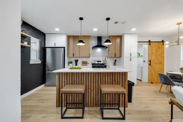 a kitchen with stainless steel appliances granite countertop a refrigerator a stove a sink dishwasher a dining table and chairs with wooden floor