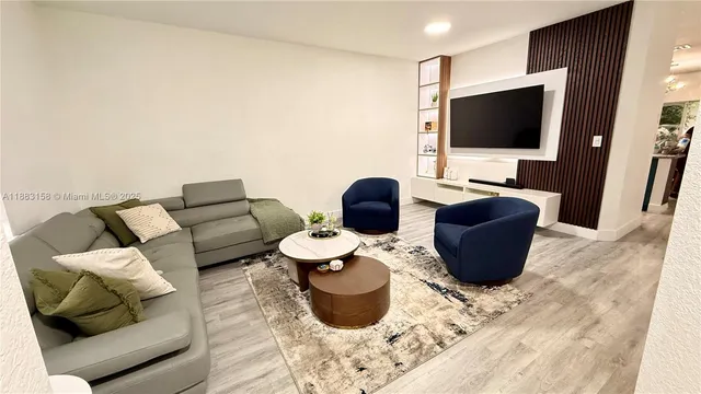 a living room with furniture a flat screen tv and kitchen view