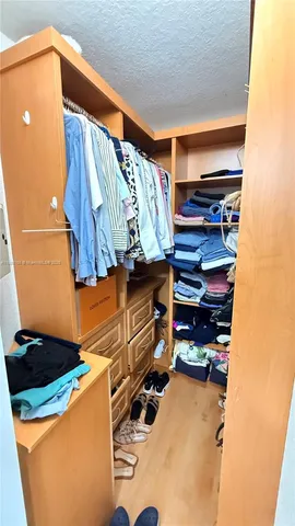 a view of walk in closet with clothes and shoes