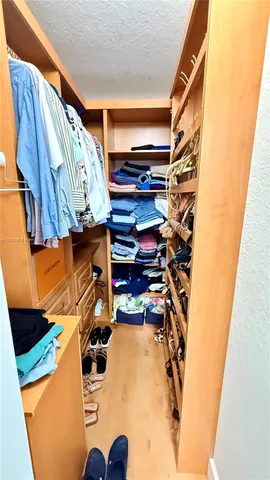 a view of walk in closet with clothes and shoes