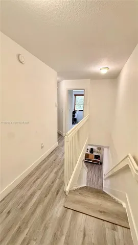a view of a hallway with wooden floor and living room