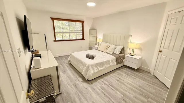 a bedroom with a bed and a flat tv screen on the dresser