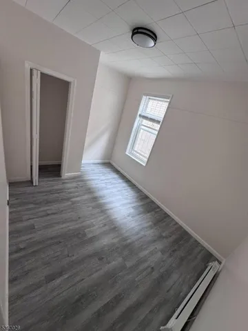 an empty room with wooden floor windows and entrance