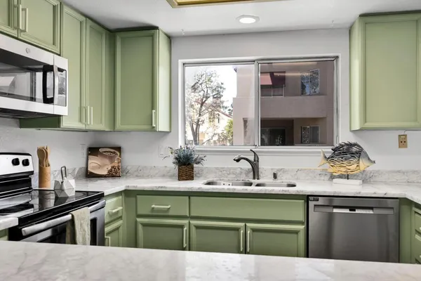 a kitchen with granite countertop a sink cabinets and stainless steel appliances