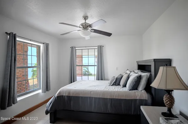 a living room with furniture a ceiling fan a lamp and a window