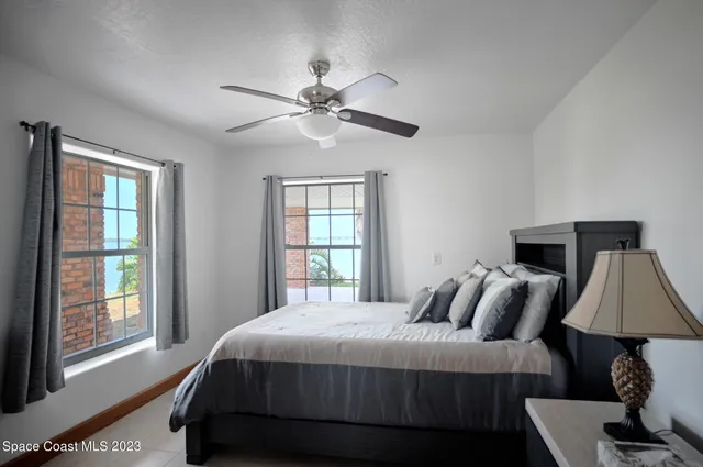 a living room with furniture a ceiling fan a lamp and a window