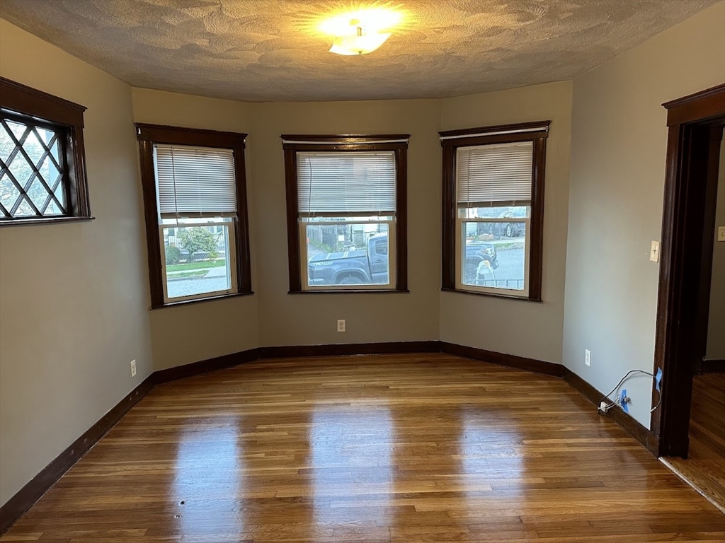 90 Boylston Street, Unit 1 Watertown, MA 02472 - Photo 4 of 16 an empty room with wooden floor and windows