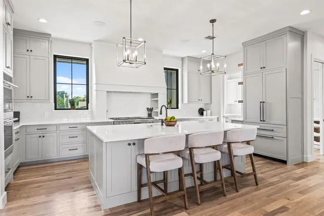 a kitchen with a dining table chairs wooden floor and white cabinets