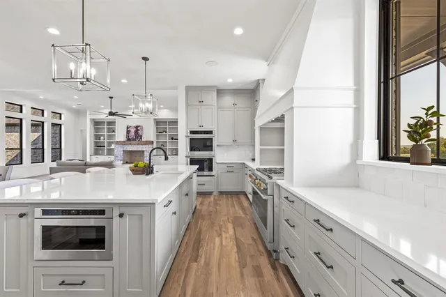 a large kitchen with kitchen island a stove a sink dishwasher and white cabinets with wooden floor