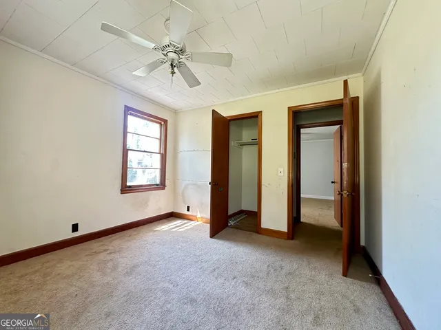 an empty room with chandelier fan and windows