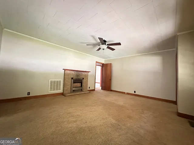 a view of an empty room with a ceiling fan and window