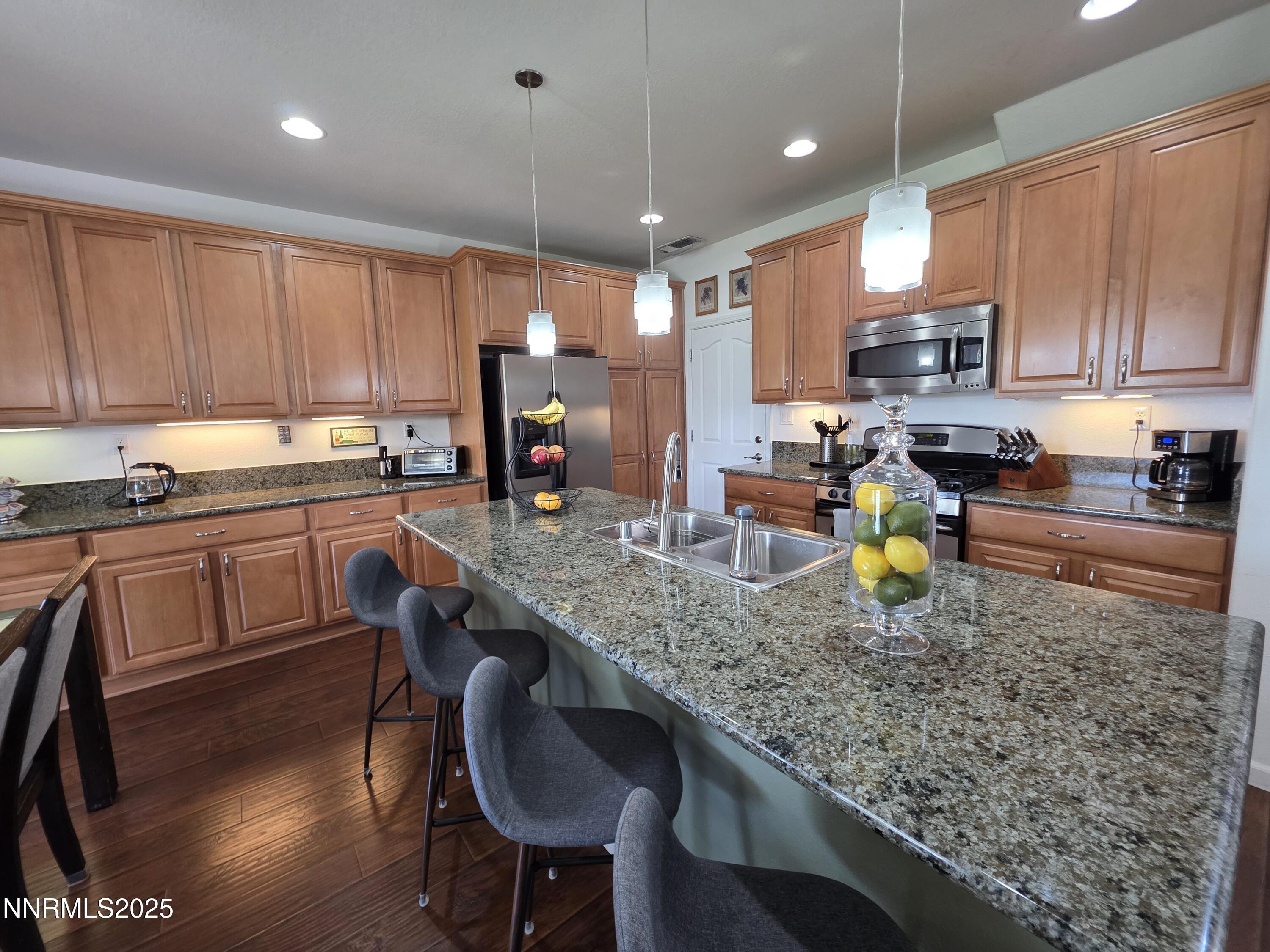 10677 Fire Poppy Circle Reno, NV 89521 - Photo 11 of 45 a kitchen with stainless steel appliances granite countertop a sink a stove a table and chairs