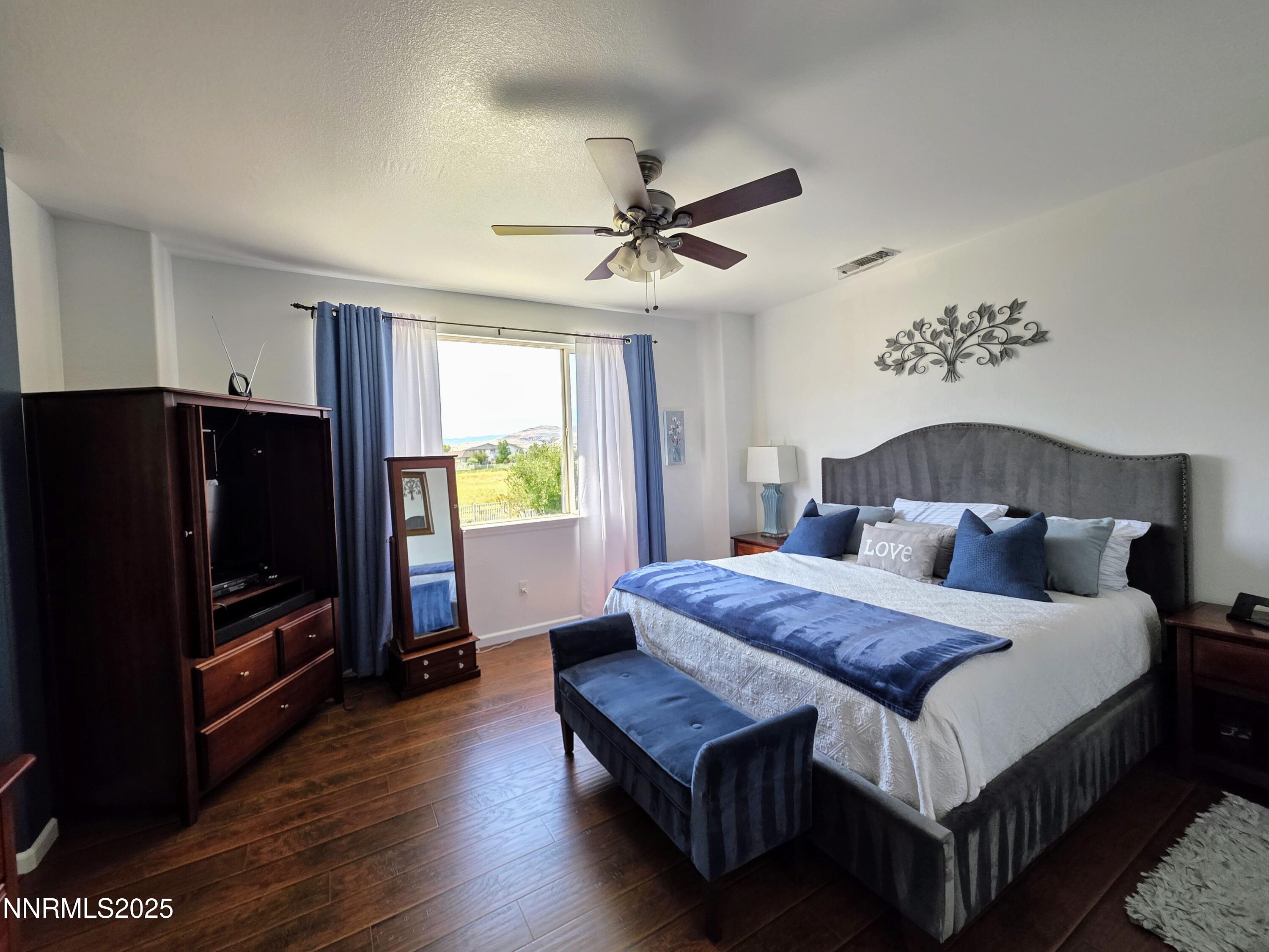 10677 Fire Poppy Circle Reno, NV 89521 - Photo 28 of 45 a bedroom with a bed table flat screen tv and a window