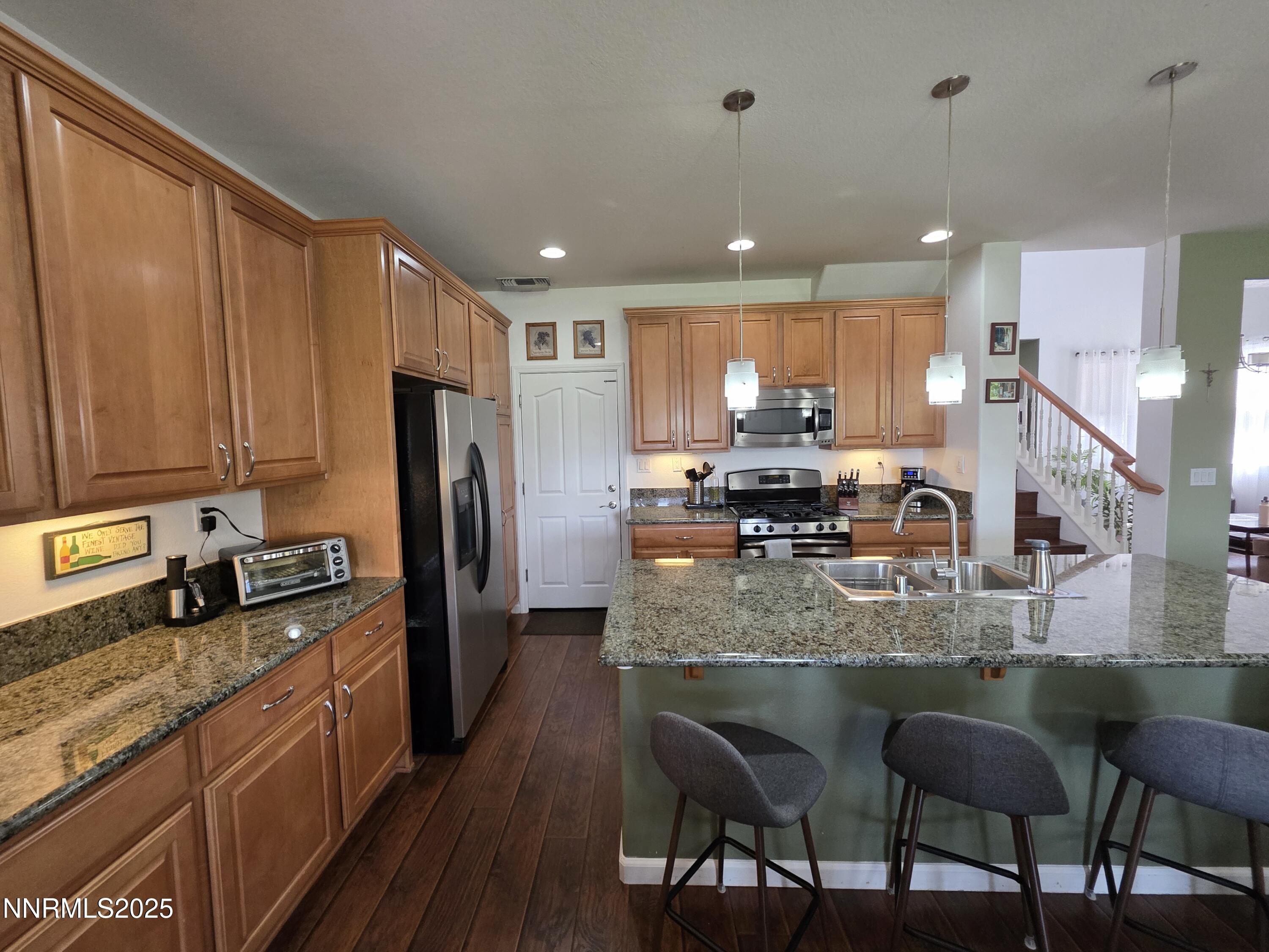 10677 Fire Poppy Circle Reno, NV 89521 - Photo 35 of 45 a kitchen with stainless steel appliances granite countertop a stove a sink a refrigerator white cabinets with wooden cabinets and chairs