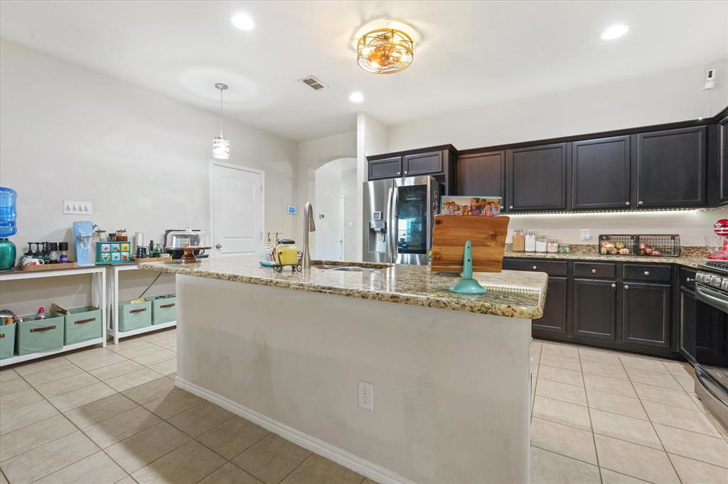 3801 Surf Street Denton, TX 76208 - Photo 8 of 29 Kitchen featuring a center island with sink, light tile patterned floors, and light stone counters